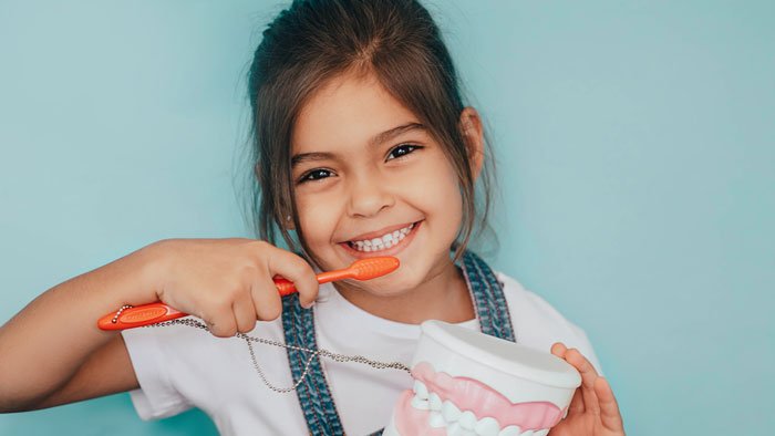 little girl posing with a large toothbrush 