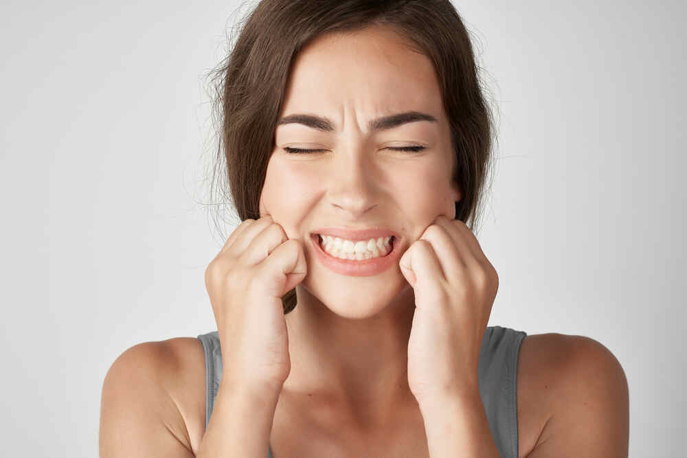 A person wincing in pain due to tooth sensitivity